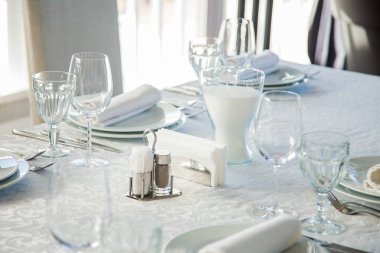 Çatal bıçak takımı ve gözlük bir beyaz masa örtüsü ile kaplı uzun bir masa