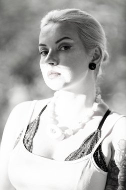 Bej elbiseli, boncuklu bir sarışının siyah beyaz portresi.