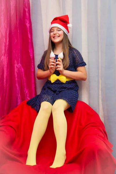 女の子で青エレガントなドレスにクリスマスのおもちゃで手に赤いアームチェア — ストック写真