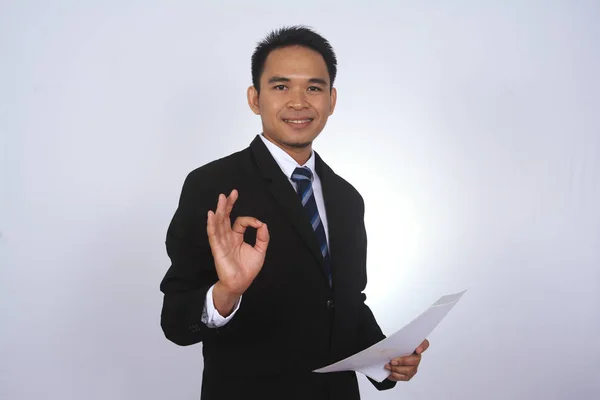 Boldog fiatal ázsiai üzletember, a papír, és bemutatja az ok jele elszigetelt fehér — Stock Fotó