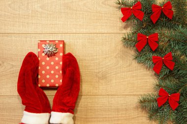 Yeni yıl / yılbaşı hediye paketi, eller kırmızı eldiven ve ağaç ahşap arka plan şablonu üzerinde kırmızı yay ile