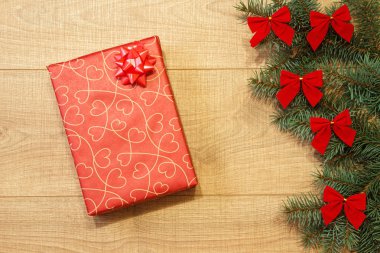 Yeni yıl / yılbaşı hediye paketi, ağaç ahşap arka plan şablonu üzerinde kırmızı yay ile