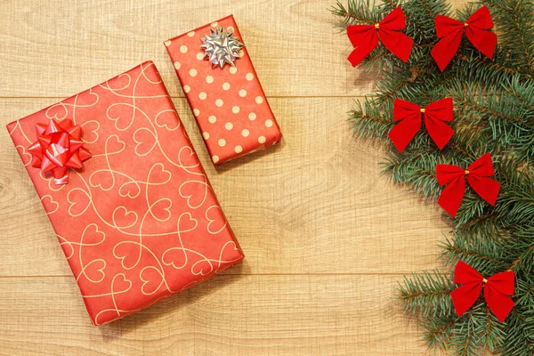 Yeni yıl / yılbaşı hediyeleri paket, ağaç ahşap arka plan şablonu üzerinde kırmızı yay ile