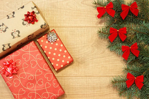 Yeni yıl / yılbaşı hediyeleri paket, ağaç ahşap arka plan şablonu üzerinde kırmızı yay ile