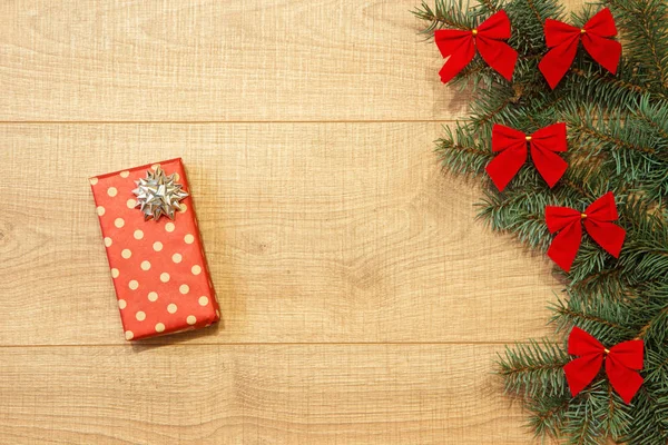 Yeni yıl / yılbaşı hediye paketi, ağaç ahşap arka plan şablonu üzerinde kırmızı yay ile