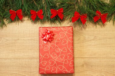 Yeni yıl / yılbaşı hediye paketi, ağaç ahşap arka plan şablonu üzerinde kırmızı yay ile