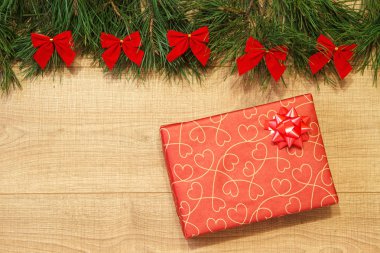 Yeni yıl / yılbaşı hediye paketi, ağaç ahşap arka plan şablonu üzerinde kırmızı yay ile