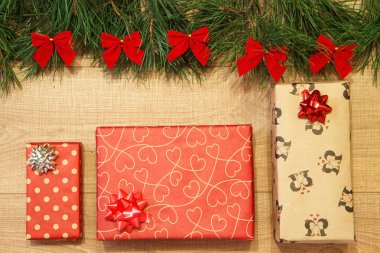 Yeni yıl / yılbaşı hediyeleri paket, ağaç ahşap arka plan şablonu üzerinde kırmızı yay ile