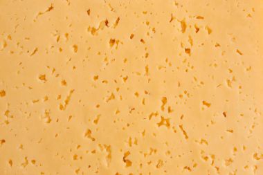 Background of fresh yellow Swiss cheese with holes.Close up of texture of cheesecake background. Surface of cheese texture. Bake cheese homemade. Rough texture surface of delicious cheese. Original and soft cheesecake clipart