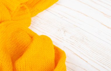 Beyaz ahşap arka planda parlak sarı örülmüş yün.