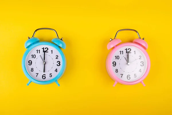 Two Alarm Clocks Bright Yellow Background Showing Different Time Concept 스톡 이미지