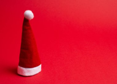 Noel Baba şapkası parlak kırmızı arka planda Noel konsepti olarak (minimal stil), metin için sağdaki boşluğu kopyala