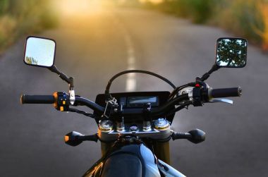 Motorcycle steering against the background of the road and sunset clipart