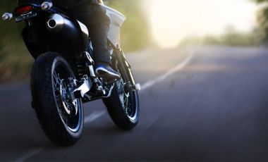 Bir motosikletçi hızda karayolu üzerinde güneş doğarken rides