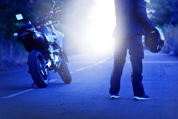 Motorcyklisten stannade och tog av sig sin hjälm på den månbelysta vägen. Natt kollision. — Stockfoto