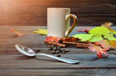 Bir fincan kahve sonbahar çevrili ile sonbahar naziklerdi ahşap bir masaya bırakır. Natürmort sonbahar ruh hali ile.