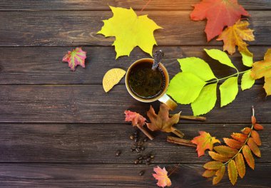 Isınma kahve ile sonbahar arka plan, bu ahşap bir masa üzerinde duran ve sonbahar yaprakları ile dekore edilmiştir. Yukarıdan görüntülemek.