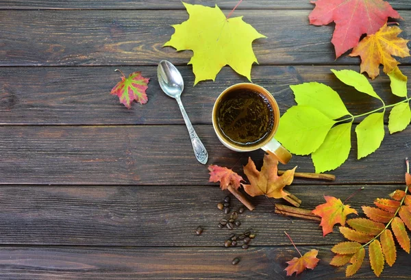 A cup of fragrant coffee on a wooden table surrounded by colorful autumn leaves background — Stock Photo, Image