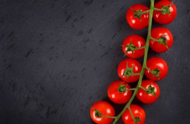 Karanlık bir taş zemin üzerine kırmızı kiraz domates Şubesi.