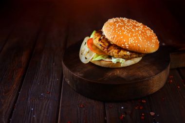 Büyük, lezzetli bir biftek ile geleneksel Amerikan hamburger yemek makro. Yatay Yönlendirme. Burger bir meşe mutfak masasında.