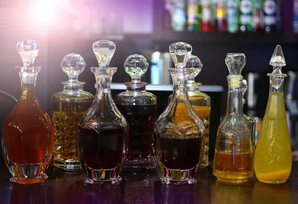 A group of decanters stands on a bar counter of a restaurant.