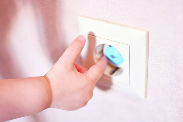 Children finger in a childproof plug. Home Safety plug socket for baby protection. Power cover gadget. 