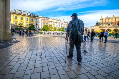Krakow, Polonya - 15 Ekim 2019: Şehir meydanında yürümek için koltuk değneği kullanan adam