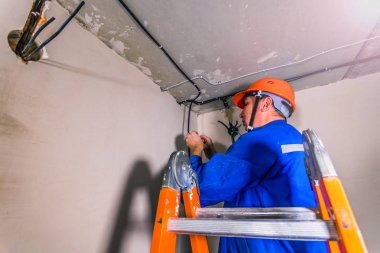 Profesyonel elektrikçi tavana elektrik tesisatı kuruyor