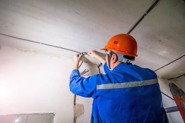 Elektrikçi başlıklı ve üniformalı, elektrikle çalışıyor.