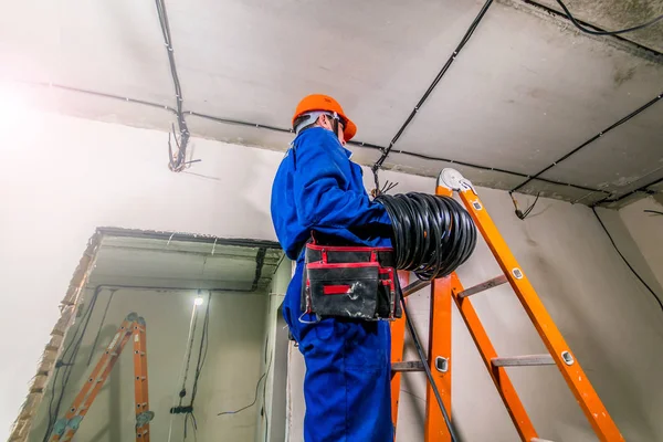 Eletricista Chapéu Duro Uniforme Uma Escada Segurando Rolo Cabo Suas — Fotografia de Stock