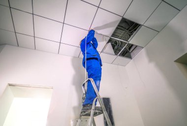 Elektrikçi bir ofisin tavanına diyot aydınlatma bandı monte eder.