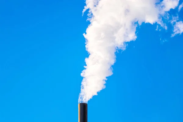 Industrial smoke from the pipe on a blue sky background. Environment pollution and global warming idea.