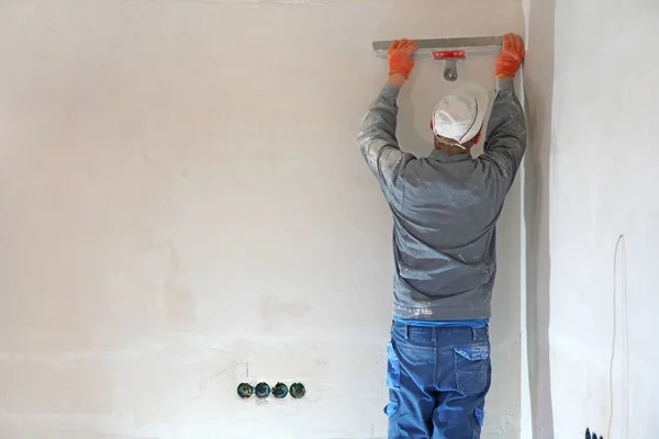 Guest worker. Worker man on earnings. Wall putty. Worker plastering a wall with trowel.