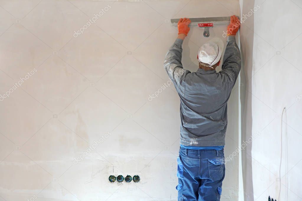 Guest worker. Worker man on earnings. Wall putty. Worker plastering a wall with trowel. 
