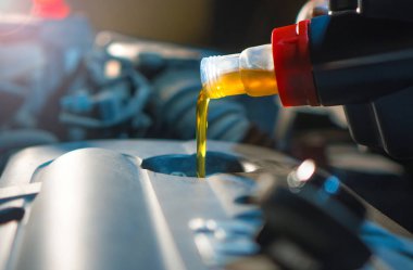 Motor yağı değişimi. Taze motor yağı teneke kutudan otomobil motoruna akıyor. Düzgün araba bakımı geçmişi.