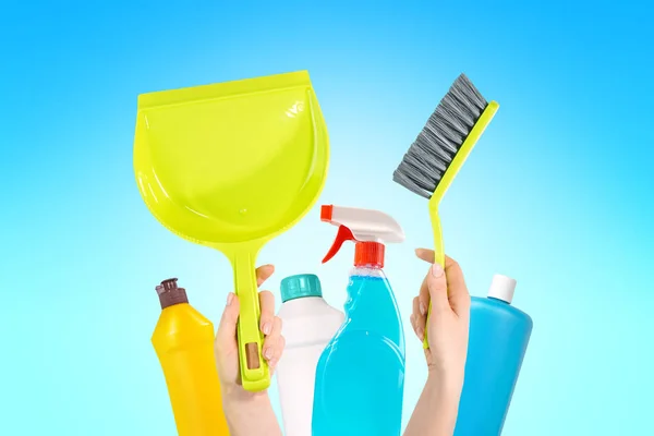 Cleaning service concept. Household chemicals and housewife hands with broom and duspan.