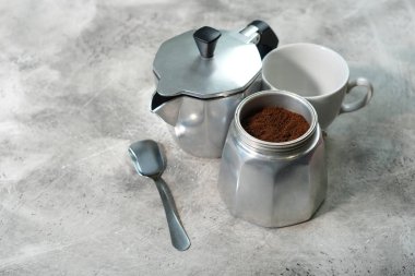 Gayzer kahve makinesi, beyaz bardak, şık masada kaşık.