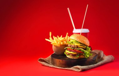 Duble sığır etli ev yapımı hamburger, kızarmış patates ve içecek..
