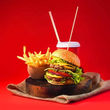 Duble sığır etli hamburger, kızarmış patates ve içecek. Kare yönelimi.