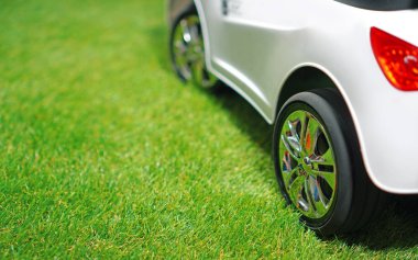 Children electric car on a green artificial grass. Copy space.