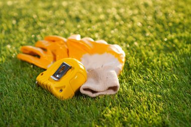 Artificial grass background with protective glooves and measuring tape