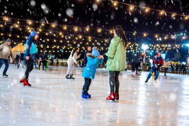 Skating rink. Mom with daughter at the ice rink. It snows.