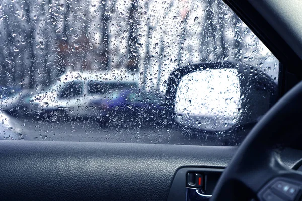 Driving in rainy weather. Side window on the driver side with rain drops.