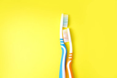 Diş fırçası sarı arka planda başka bir diş fırçası bırakıyor.