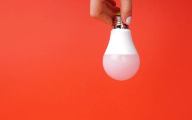 Kırmızı arka planda dişi elinde ampul, yaratıcı ya da fikir olarak