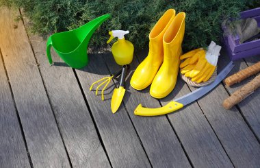 Bahçıvanlık. Yağmur botları ve bahçe işleri aletleri ahşap terasta