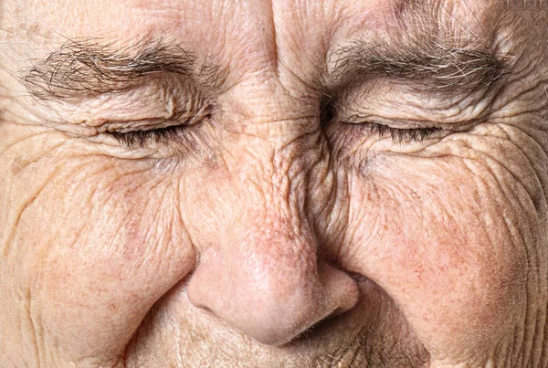 Wrinkled old face close up. Portrait of an old woman with closed eyes