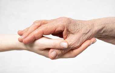 Yaşlı kırışık el, genç elde yatıyor. Yaşlılara özen gösterin.