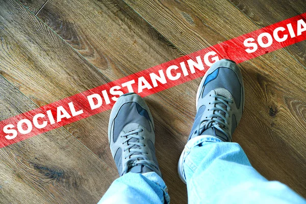 Social distancing in epidemic time concept with male legs  near the red line with text Social distancing