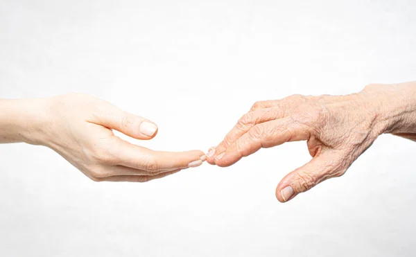 Una mano joven busca una mano vieja. Ayuda para el concepto de ancianos — Foto de Stock